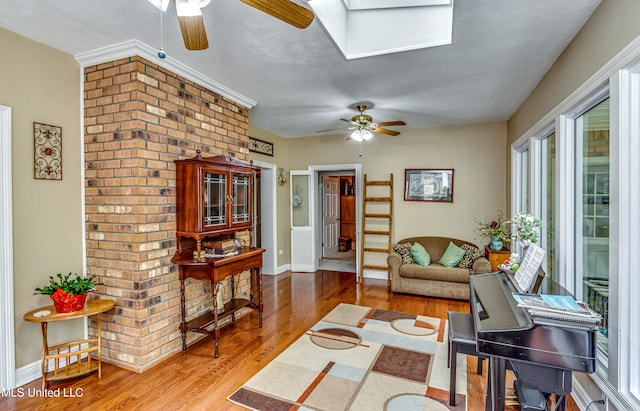 living room with a skylight, hardwood / wood-style flooring, and ceiling fan