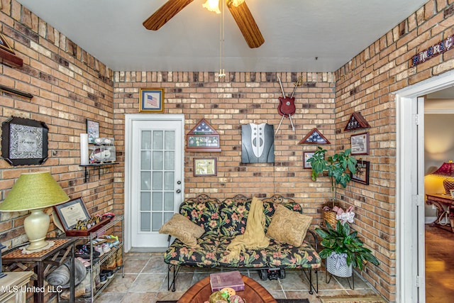 living room with light hardwood / wood-style flooring, ceiling fan, and brick wall