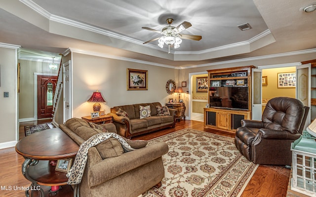 living room featuring ornamental molding, hardwood / wood-style floors, ceiling fan, and a raised ceiling