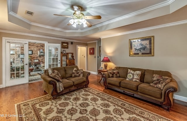 living room featuring a tray ceiling, wood-type flooring, ceiling fan, and crown molding