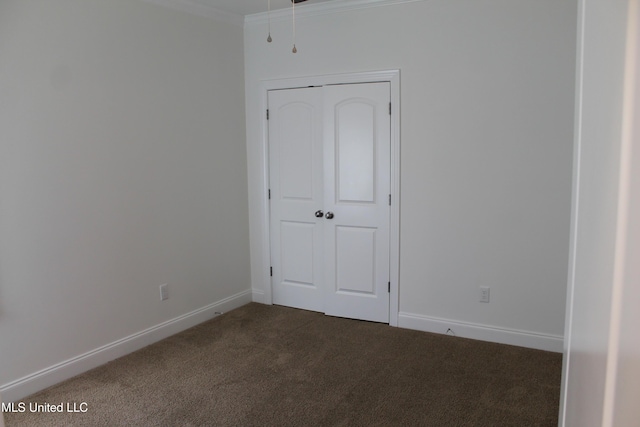 unfurnished bedroom featuring dark colored carpet, a closet, and crown molding