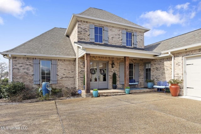 traditional home with roof with shingles, a porch, and brick siding