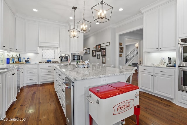 kitchen featuring white cabinetry, appliances with stainless steel finishes, dark wood-style floors, an island with sink, and pendant lighting