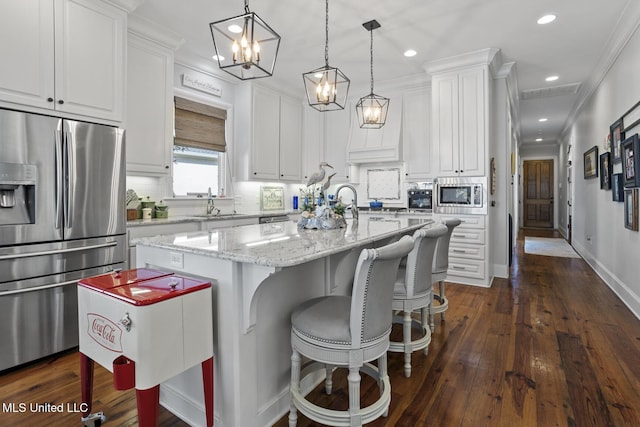 kitchen with stainless steel appliances, a center island, white cabinets, light stone countertops, and pendant lighting