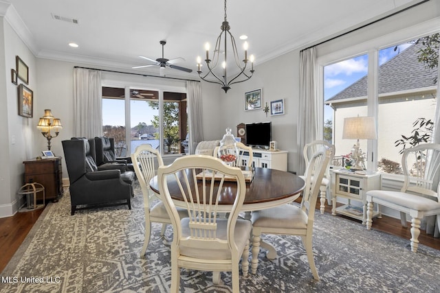 dining area with ceiling fan with notable chandelier, dark wood-type flooring, visible vents, baseboards, and crown molding