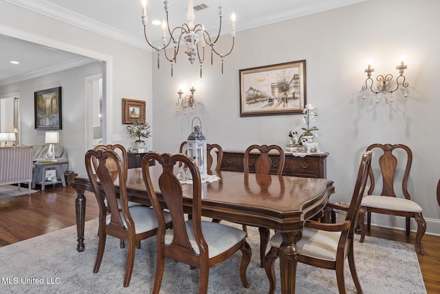 dining space with visible vents, baseboards, ornamental molding, wood finished floors, and an inviting chandelier