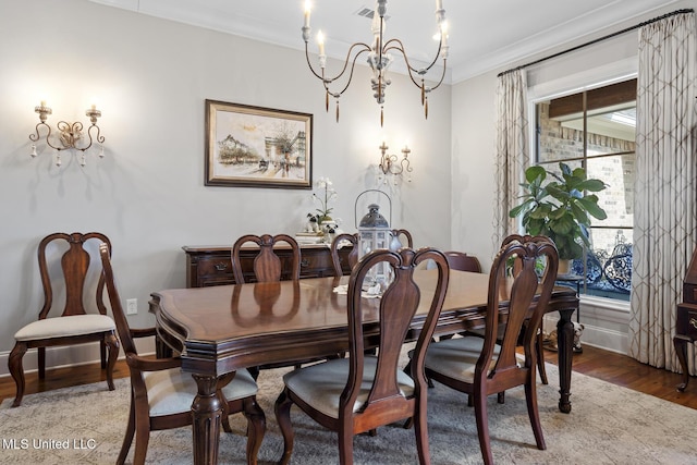 dining room featuring a chandelier, wood finished floors, visible vents, baseboards, and ornamental molding