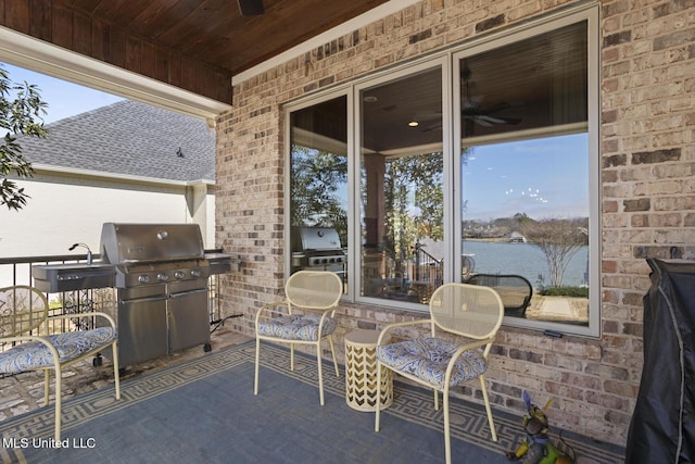 view of patio with a water view, a grill, and ceiling fan