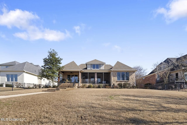 view of front facade with brick siding, a front yard, fence, and a sunroom