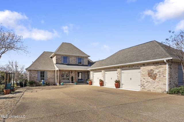 traditional home featuring a garage, concrete driveway, brick siding, and roof with shingles