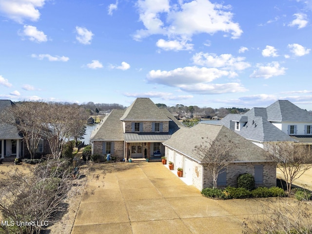 view of front of house featuring a garage, brick siding, concrete driveway, a residential view, and a standing seam roof