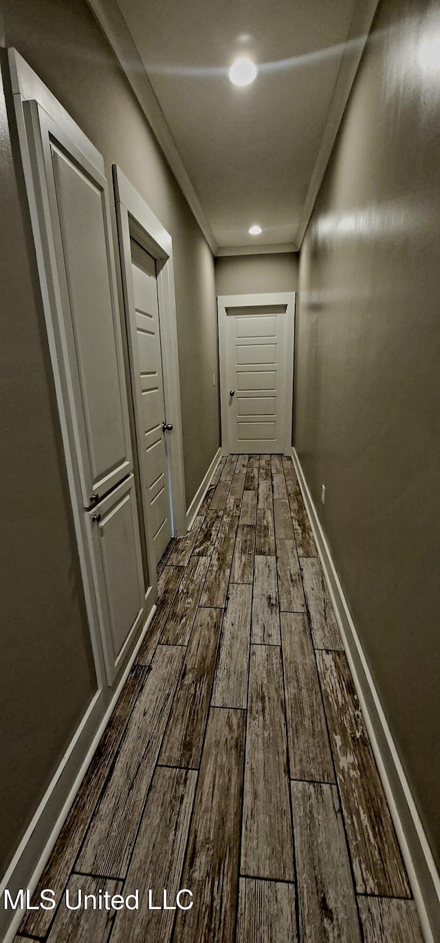 corridor featuring baseboards, dark wood-style flooring, and crown molding