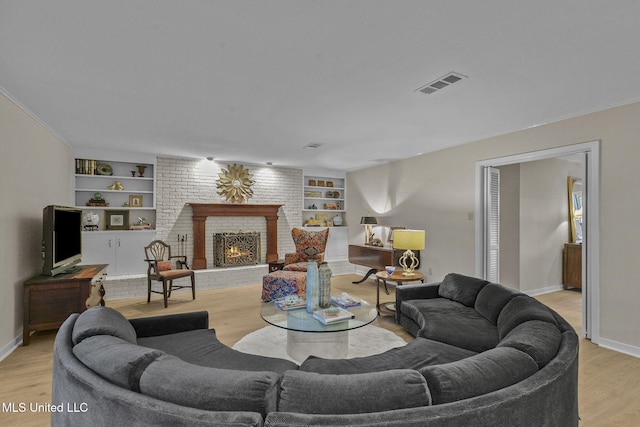 living room with a fireplace, light hardwood / wood-style flooring, and built in shelves