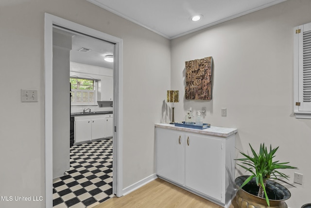 bar with white cabinetry, sink, and light hardwood / wood-style floors