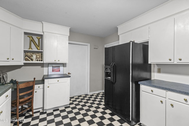 kitchen featuring white cabinetry and black fridge