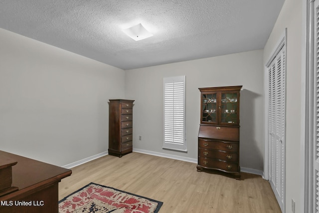 interior space featuring light hardwood / wood-style flooring, a textured ceiling, and a closet