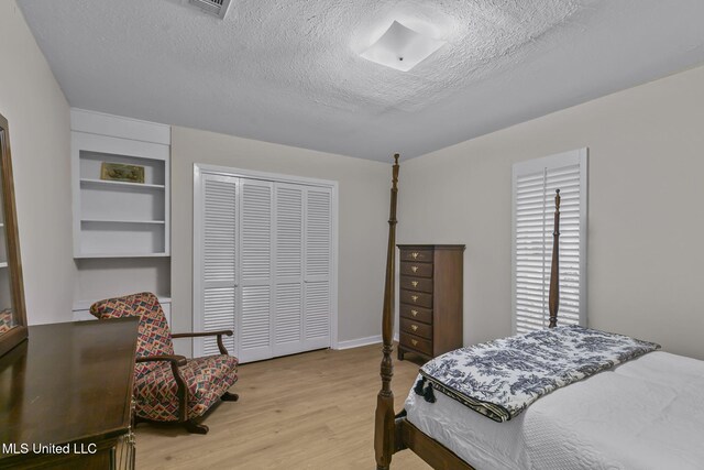 bedroom with light wood-type flooring, a textured ceiling, and a closet