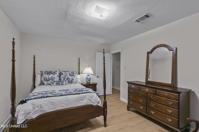 bedroom featuring light hardwood / wood-style floors and a textured ceiling