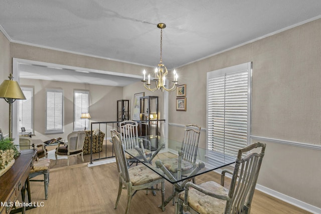 dining room with light wood-type flooring, an inviting chandelier, and ornamental molding