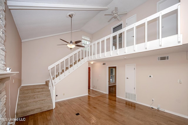 unfurnished living room featuring high vaulted ceiling, wood-type flooring, ceiling fan, and a stone fireplace