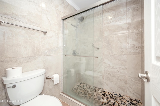 bathroom featuring ornamental molding, a shower with door, tile walls, and toilet