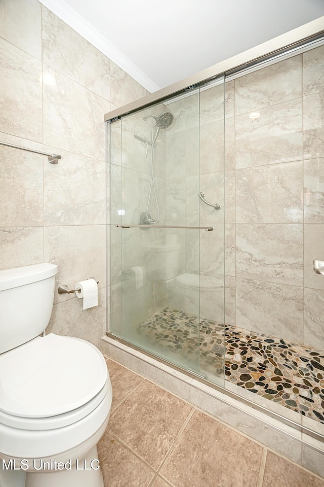 bathroom with tile walls, toilet, ornamental molding, and a shower with shower door