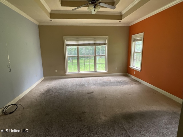 empty room featuring a raised ceiling, ornamental molding, a ceiling fan, carpet floors, and baseboards