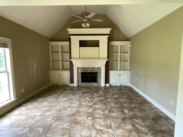 unfurnished living room featuring ceiling fan, lofted ceiling, a tiled fireplace, and baseboards
