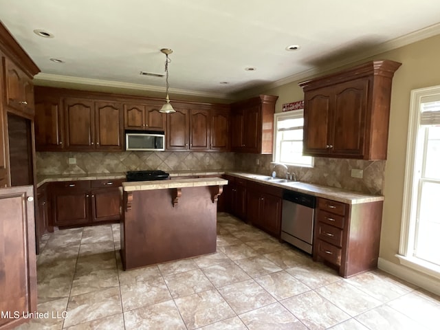 kitchen featuring stainless steel appliances, a center island, tasteful backsplash, crown molding, and tile counters
