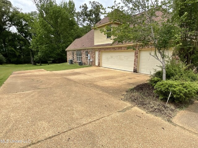 view of front of home with concrete driveway, brick siding, central AC, and a front yard