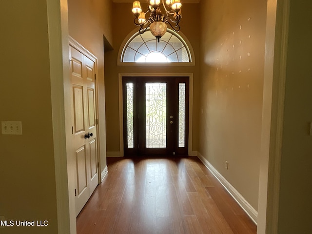 entrance foyer with a chandelier, wood finished floors, and baseboards