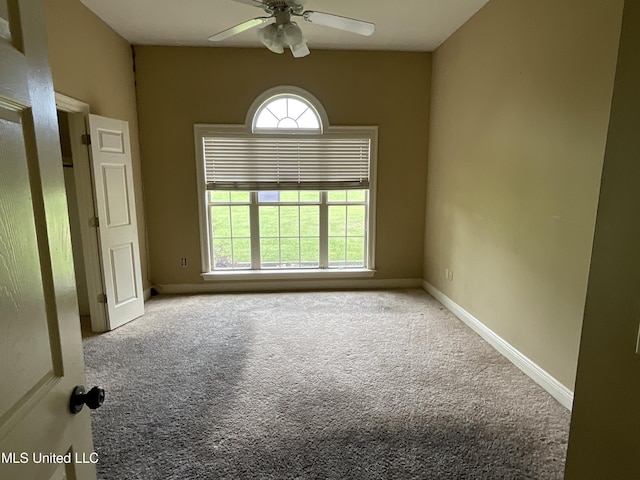 carpeted empty room with a ceiling fan and baseboards