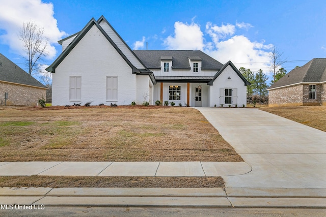 view of front of property with metal roof, a standing seam roof, a front lawn, a porch, and brick siding