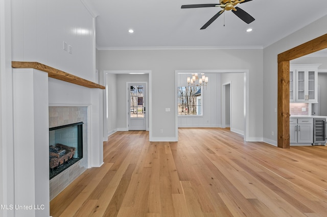 unfurnished living room with light wood-type flooring, baseboards, crown molding, and a tile fireplace