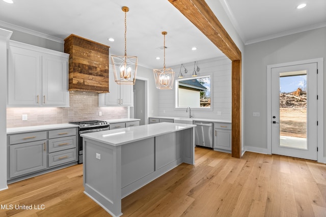 kitchen with a wealth of natural light, light countertops, hanging light fixtures, appliances with stainless steel finishes, and a kitchen island