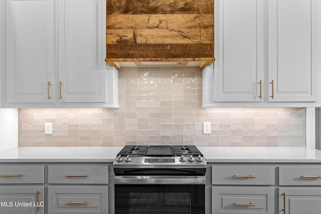 kitchen with tasteful backsplash, gas stove, and gray cabinetry