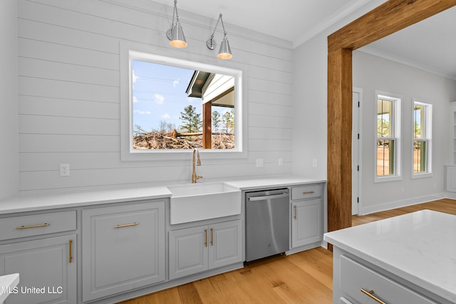 kitchen with dishwasher, light countertops, crown molding, light wood-type flooring, and a sink