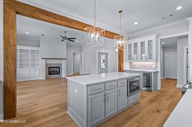 kitchen featuring stainless steel appliances, light countertops, glass insert cabinets, open floor plan, and a kitchen island