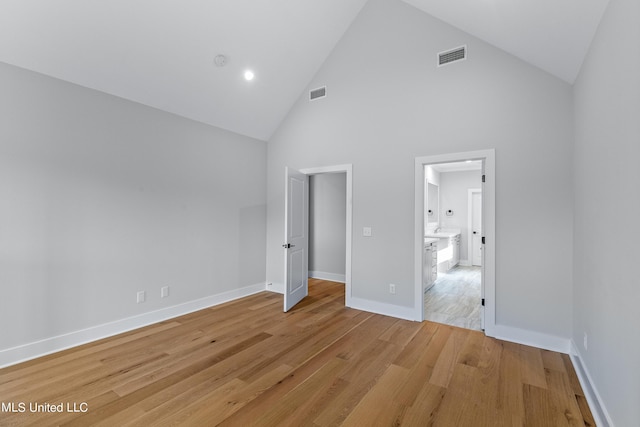 unfurnished bedroom with high vaulted ceiling, light wood-type flooring, visible vents, and baseboards