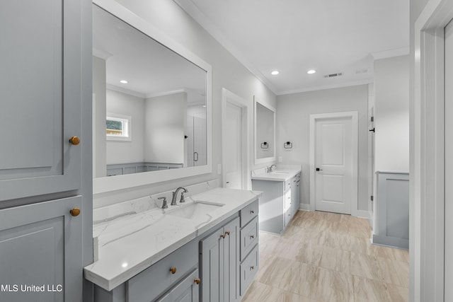 full bathroom with ornamental molding, two vanities, visible vents, and a sink