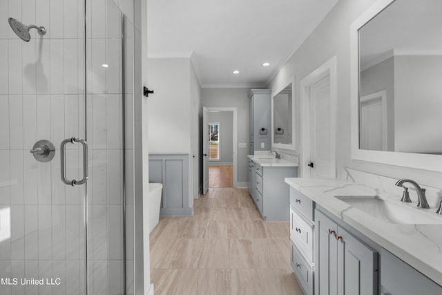 bathroom with ornamental molding, a stall shower, two vanities, and a sink