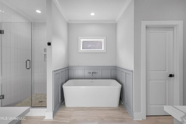 full bath featuring a wainscoted wall, vanity, a freestanding bath, a stall shower, and crown molding