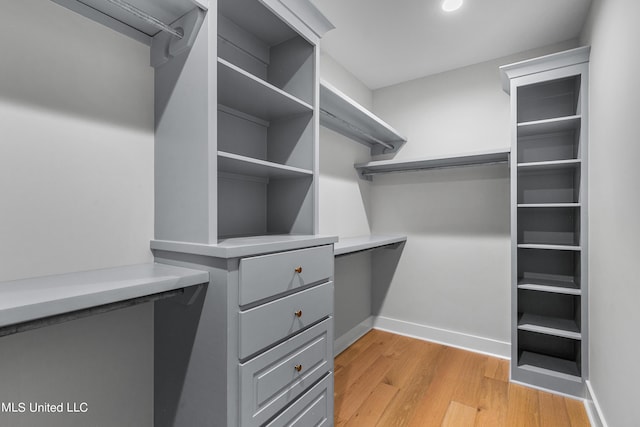 walk in closet with light wood finished floors