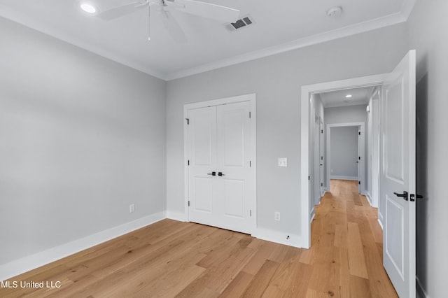 unfurnished bedroom with light wood-style flooring, visible vents, baseboards, and ornamental molding