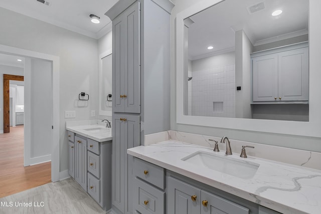 bathroom with crown molding, visible vents, two vanities, and a sink