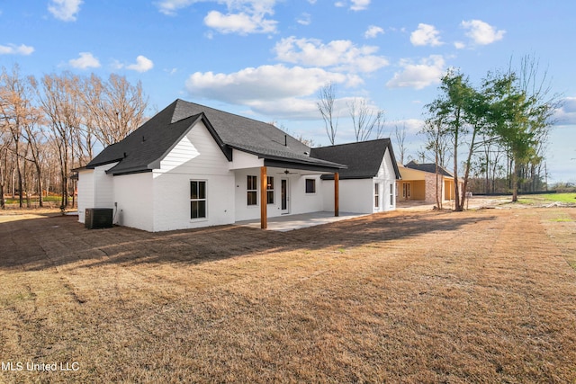 back of property featuring a patio, central AC unit, a lawn, and a shingled roof