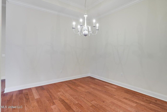 empty room featuring an inviting chandelier, hardwood / wood-style floors, and crown molding