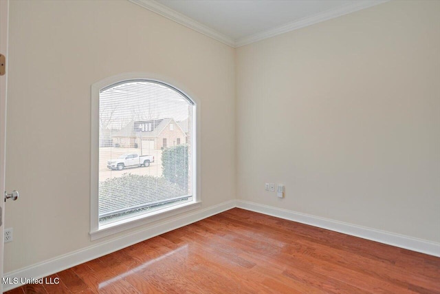 spare room featuring crown molding, a healthy amount of sunlight, and wood-type flooring