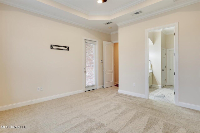 unfurnished bedroom with a tray ceiling, crown molding, light carpet, and ensuite bath