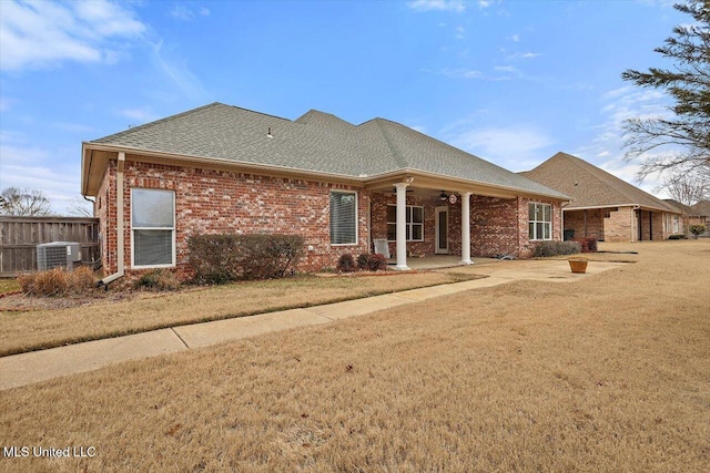 rear view of house featuring central AC unit, a yard, and a patio